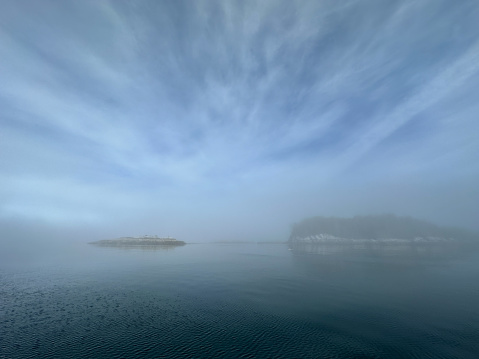 Anchorage in Stryker Island, British Columbia with early morning fog. Island and blue, cloudy skies reflecting on the water.