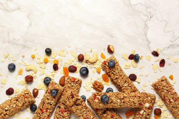 istock Tasty granola bars and ingredients on white marble table, flat lay. Space for text 1937667921