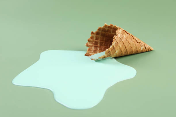 istock Melted ice cream and wafer cone on green background, closeup 1937670092