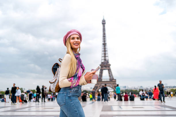 Young smiling woman tourist walking in front of the Eiffel Tower in Paris, France