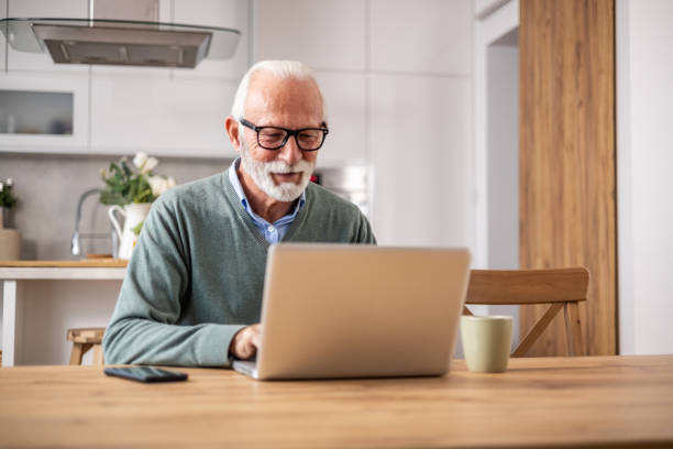 istock A pensioner sits at the dining room table and works on a laptop 1937726800