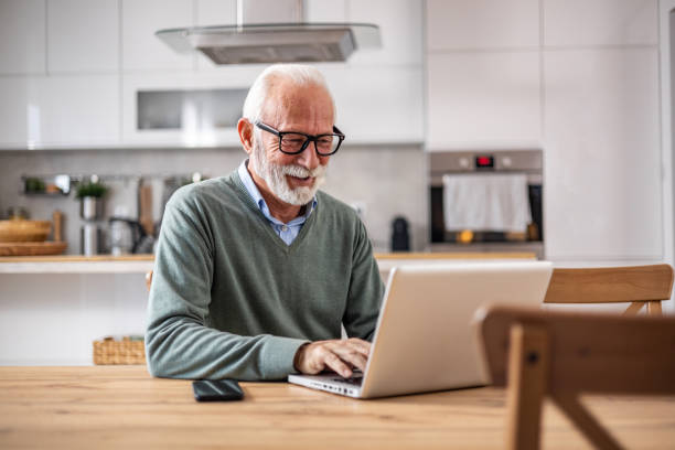 istock A pensioner sits at the dining room table and works on a laptop 1937727864