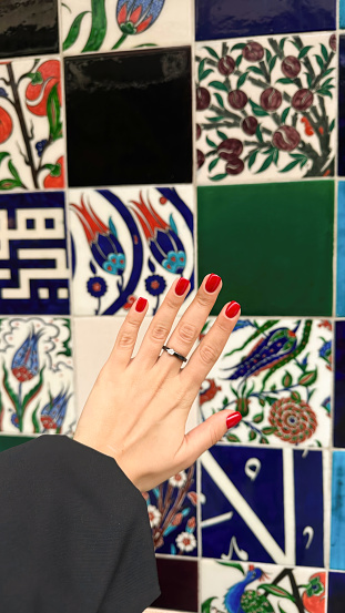 Mosaic Glamour: Red Manicured Hand on Tiled Background