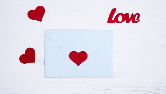 Romantic message for Valentine's day. Flatlay composition with envelope and red hearts for Valentine's day on white background. Top view.