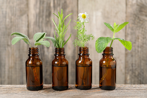 Bottles with essential oils and plants on wooden table