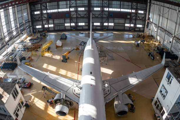 Top view of a white passenger jet plane in the aviation hangar Top view of a white passenger jet plane in the aviation hangar. Airliner under maintenance. Checking mechanical systems for flight operations airplane hangar stock pictures, royalty-free photos & images