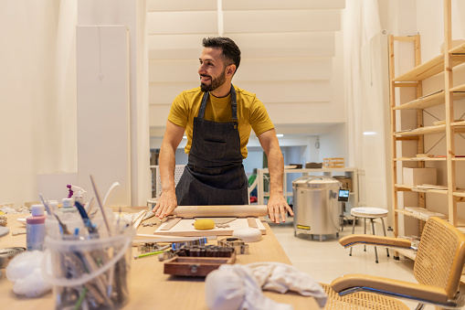 young man in pottery workshop kneading clay