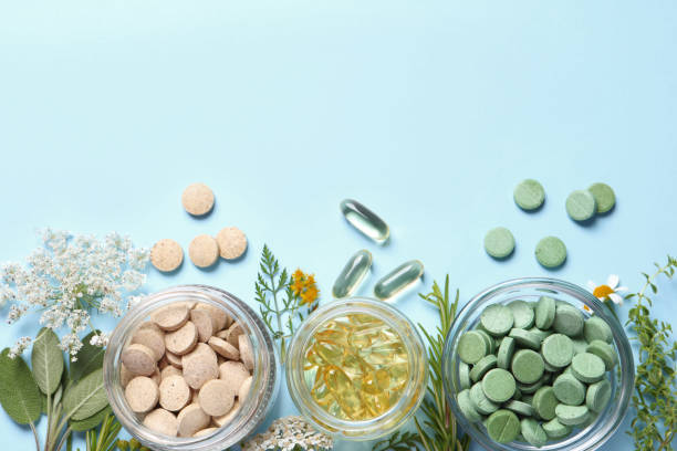 istock Different pills, herbs and flowers on light blue background, flat lay with space for text. Dietary supplements 1937763598