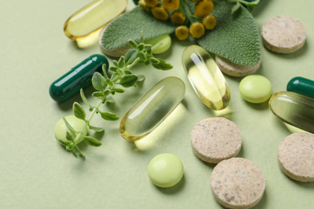 istock Different pills and herbs on light green background, closeup. Dietary supplements 1937770274
