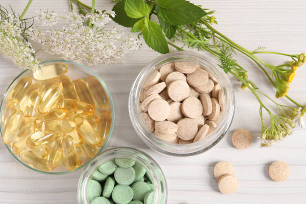 istock Different pills, flowers and herbs on white wooden table, flat lay. Dietary supplements 1937776611