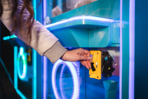 istock Close-up of woman's hands inserting a coin into a claw machine arcade game 1937778574