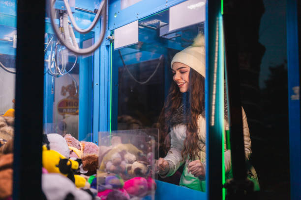 istock Beautiful young woman having fun while playing a claw machine arcade game outdoors 1937779112