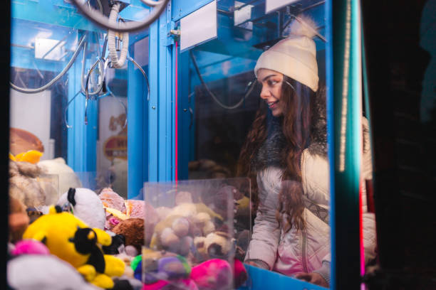 istock Beautiful young woman having fun while playing a claw machine arcade game outdoors 1937779129