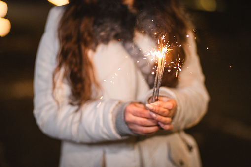 Close-up of New Year's sparklers. Young woman celebrating.
