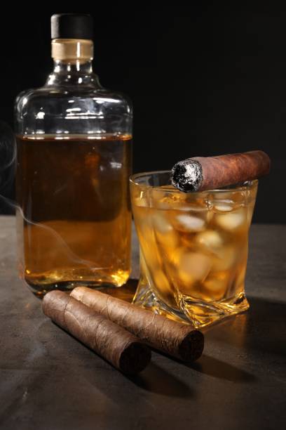 istock Cigars and whiskey on grey table against black background 1937793886
