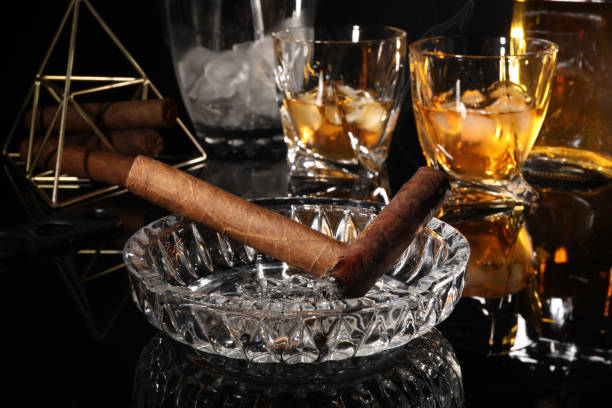 istock Burnt cigars, ashtray and whiskey on black mirror surface 1937794406