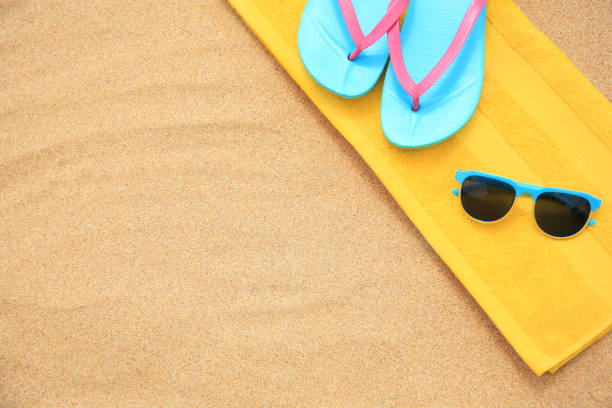 istock Yellow towel, sunglasses and flip flops on sand, top view with space for text 1937798664