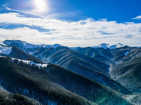 The sun radiates above Bucegi mountains in Romania during the winter