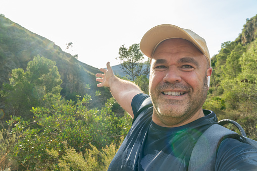 Hiker man takes a photo selfie in the mountain, showing the beautiful landscape.