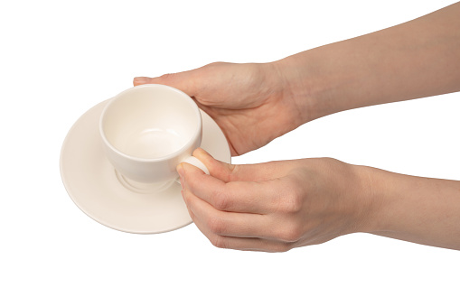 Female hand holding coffee cup and saucer isolated on a white background.