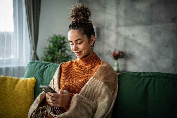 istock Happy white young woman sitting alone on sofa in living room and using technology for networking. 1937829775