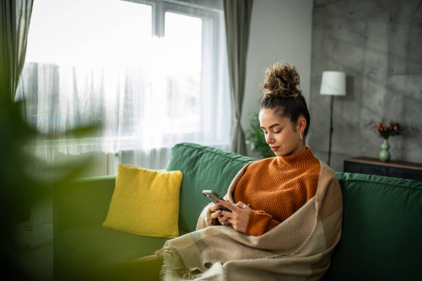 istock Happy white young woman sitting alone on sofa in living room and using technology for networking. 1937830847