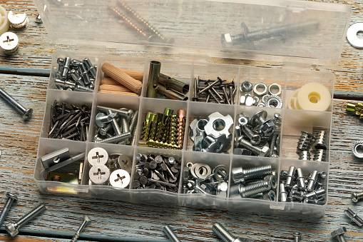 Organizer with many different fasteners on rustic wooden table, above view