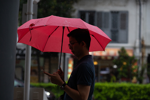 A man walks through the afternoon rain showers in the central part of Singapore City, Singapore