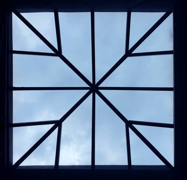 a ceiling window made of wood and glass, showing sky, with white clouds