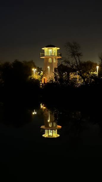 istock A glowing lighthouse in the night and its mirror reflection in the water 1937919031