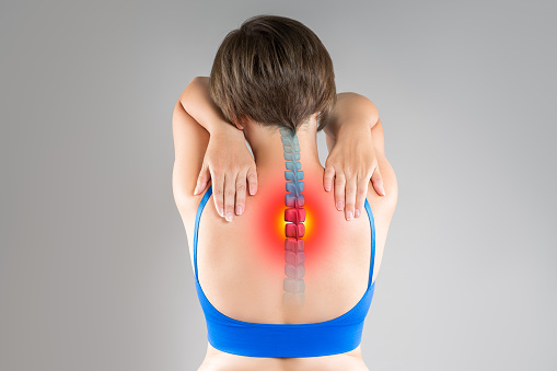 Intervertebral spine hernia, pain between the shoulder blades, woman suffering from backache, spinal disc disease, gray studio background, health problems concept