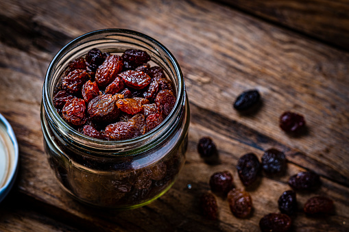 Fresh organic raisins in a glass jar shot on rustic table. High resolution 42Mp studio digital capture taken with Sony A7rII and Sony FE 90mm f2.8 macro G OSS lens
