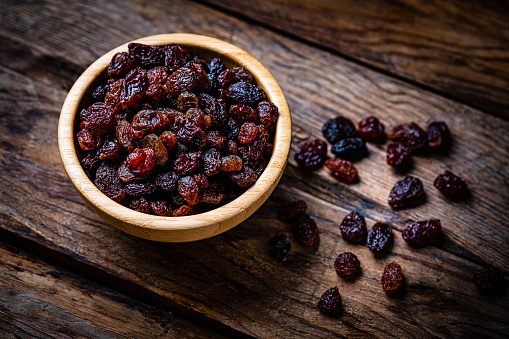 Fresh organic raisins in a bowl shot on rustic table. High resolution 42Mp studio digital capture taken with Sony A7rII and Sony FE 90mm f2.8 macro G OSS lens