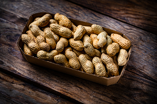High angle view of unshelled peanuts on rustic wooden table. High resolution 42Mp studio digital capture taken with Sony A7rII and Sony FE 90mm f2.8 macro G OSS lens