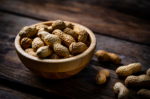 Unshelled peanuts on rustic wooden table. High resolution 42Mp studio digital capture taken with Sony A7rII and Sony FE 90mm f2.8 macro G OSS lens