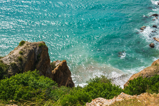 The azure sea against the backdrop of mountains and green trees.