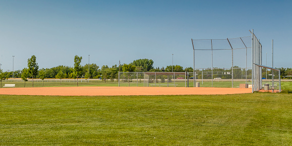 this photo is of a Baseball Field at Baseball Game with Baseball Player. the photo is first base or third base with a line foul line. the infield is dirt. and the other side of the foul line is green grass. the baseball player is an athlete to base. the photo is at a live sporting event. the lighting is natural sunlight. 