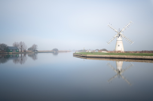 Thurne mill and reflection across Thurne staithe on a misty still morning in the Norfolk Broads Thurne, Feb 2023