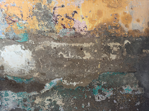 Abstract, detail, pattern of a section of multi-colored peeling paint layers on an old stone exterior wall. No people. Turkey