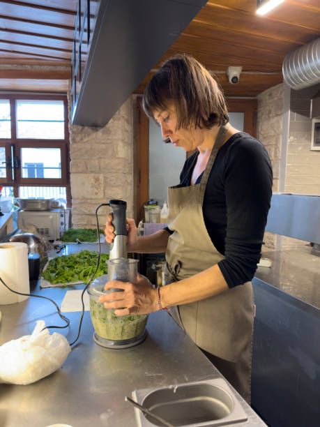 istock Professional female chef preparing food in modern restaurant kitchen. He makes appetizers with vegetables in the blender. 1938004387