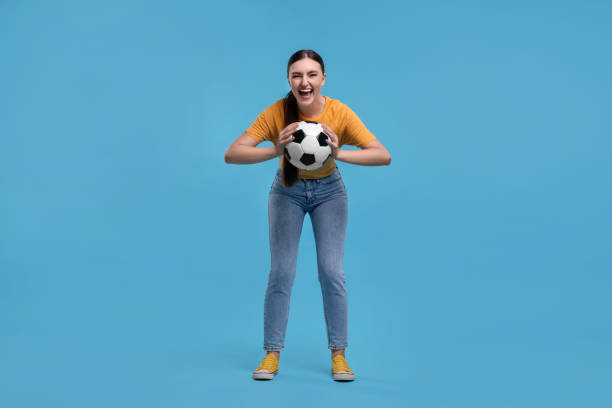 istock Happy soccer fan with ball on light blue background 1938014024
