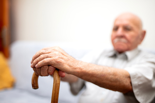 Shot of a senior man leaning in his walking stick at home