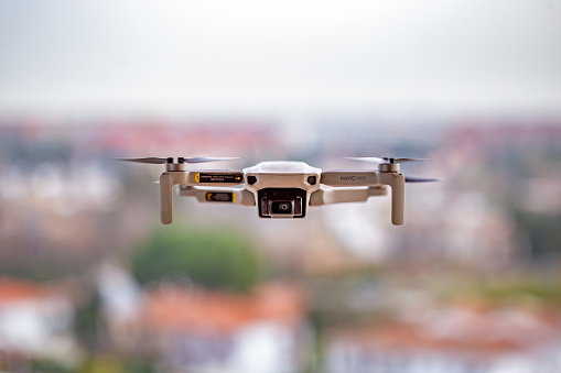 DJI Mavic Mini drone flying over a residential area at medium height to take aerial photographs