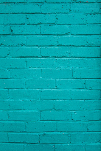 Vertical stained and peeling teal painted wall.