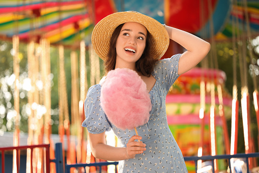 Beautiful young woman with cotton candy at funfair
