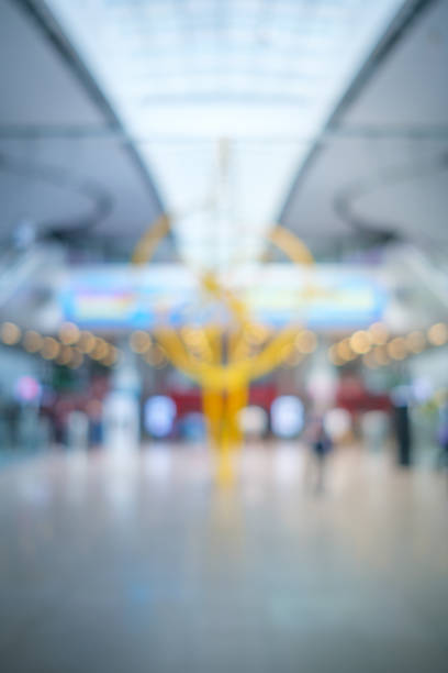 Colorful, defocused modern airport with a tall yellow sculpture, lights, and a person walking through.