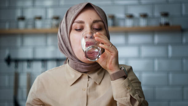 istock Headscarved woman taking her medicine while sitting in the kitchen 1938169665