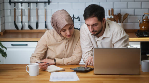 istock Married couple sitting in kitchen with laptop pay bills, use calculator count expenses, manage finances, make budget control, feel stressed 1938171295