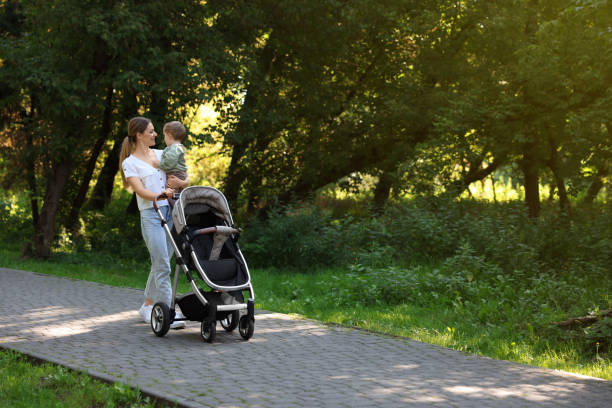 istock Happy nanny with cute little boy and stroller walking in park, space for text 1938178734