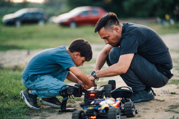 istock A boy fixing toy car overturned on a dirt road while his father helps him 1938206022